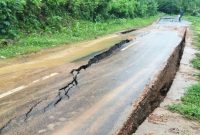 Kondisi Jalan Lintas Parado, Kabupaten Bima, tampak retak dan mengalami penurunan tanah akibat faktor alam dan pergeseran tanah, mengganggu akses transportasi serta aktivitas ekonomi warga setempat.