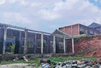 Suasana bangunan seperti ‘Rumah Hantu’ di SMAN 1 Parado Bima, ruang kelas yang belum selesai dibangun dan mulai ditumbuhi semak belukar, terlihat terbengkalai di tengah hujan, Senin (26/1/2026). Siswa terpaksa belajar dengan sistem sif (shift) agar proses KBM tetap berjalan.