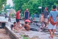 Aspal jalan Dermaga Kore yang terkelupas, warga menyingkirkan material agar kendaraan bisa melintas.