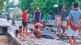 Aspal jalan Dermaga Kore yang terkelupas, warga menyingkirkan material agar kendaraan bisa melintas.