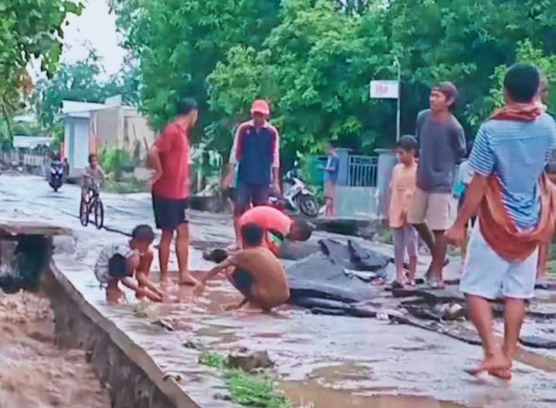 Aspal jalan Dermaga Kore yang terkelupas, warga menyingkirkan material agar kendaraan bisa melintas.