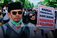 Bupati Dompu Bambang Firdaus Dengan Latar Aksi Ratusan PPPK Paruh Waktu Nakes dan Tenaga Teknis yang Menuntut Kepastian Pengangkatan Menjadi PPPK Penuh Waktu.