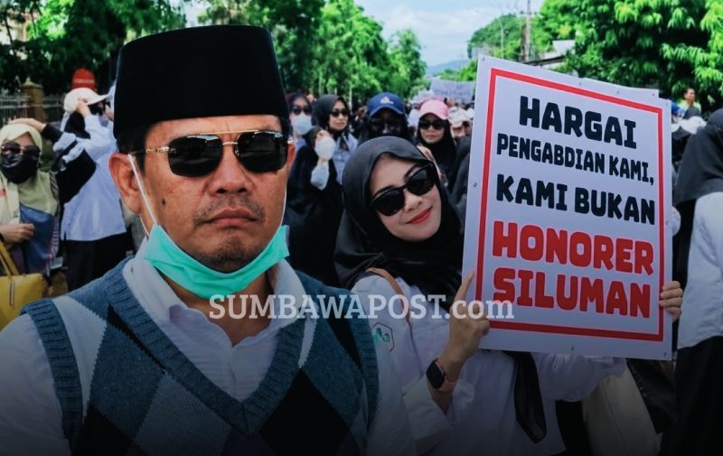 Bupati Dompu Bambang Firdaus Dengan Latar Aksi Ratusan PPPK Paruh Waktu Nakes dan Tenaga Teknis yang Menuntut Kepastian Pengangkatan Menjadi PPPK Penuh Waktu.