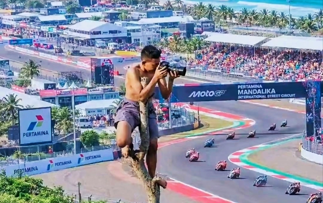Seorang Warga Memotret Jalannya Balapan MotoGP Mandalika 2026 dari atas Pohon di Kawasan Sirkuit Mandalika, Lombok Tengah, NTB.
